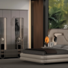 Luxurious modern bedroom with a tall mirrored wardrobe on the left and a curved upholstered bed facing large windows with greenery outside