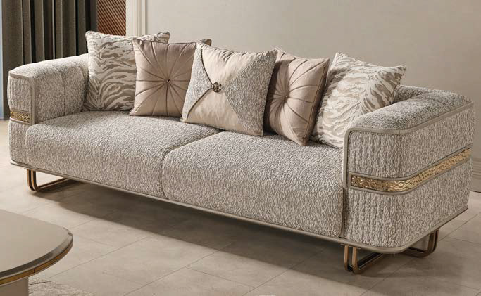 Cream textured sofa with gold metal accents and six beige decorative pillows in a contemporary living room