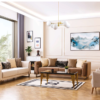 Bright living room with cream and tan sofas a glass coffee table and two cream chairs facing a wall with framed art