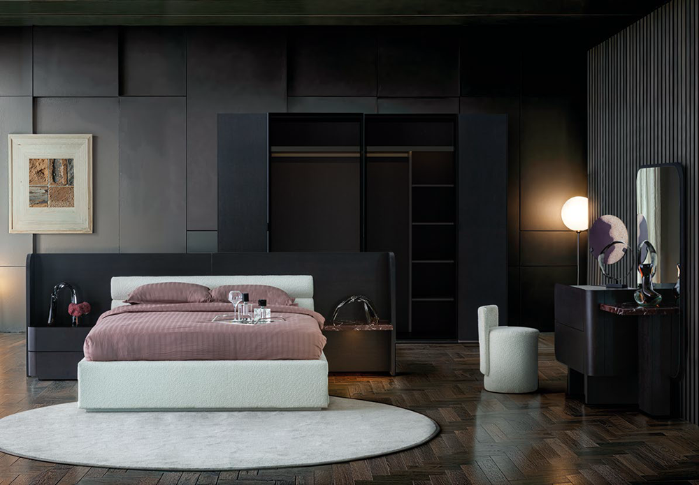 Luxurious dark bedroom with a low-profile white bed and mauve bedding on a circular white rug, flanked by black built-in wardrobes.