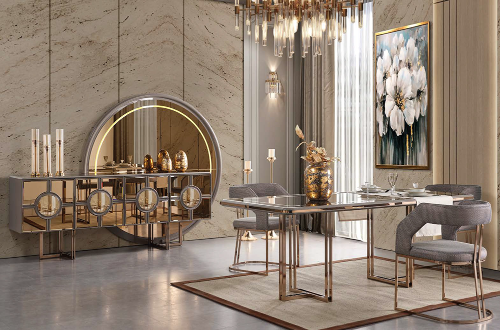 Luxurious dining room with a glass-top table, gray upholstered chairs, and gold metal frames against marble walls and a circular illuminated mirror.