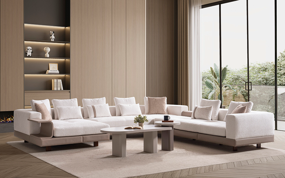 Modern beige sectional sofa in a bright living room with large floor-to-ceiling windows and a built-in wooden bookshelf.