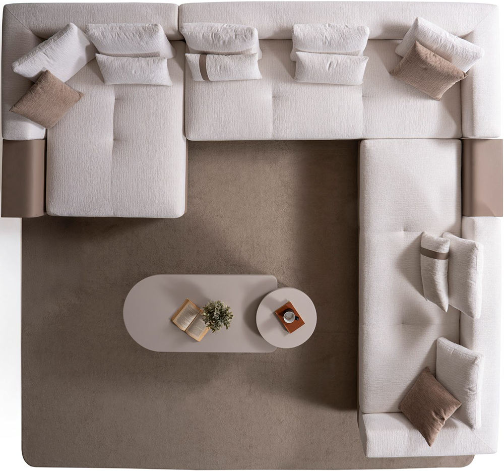 Roma Corner Set 3 Armonna Top down view of a cream sectional sofa around a large beige rug with an oval coffee table holding a book plant and cup