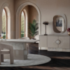 Luxurious neutral dining room with a long white table soft upholstered chairs and a beige sideboard under arched windows