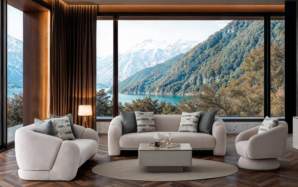 Luxurious living room with cream sofas, a circular rug, and a glass coffee table, overlooking a mountain lake through large windows