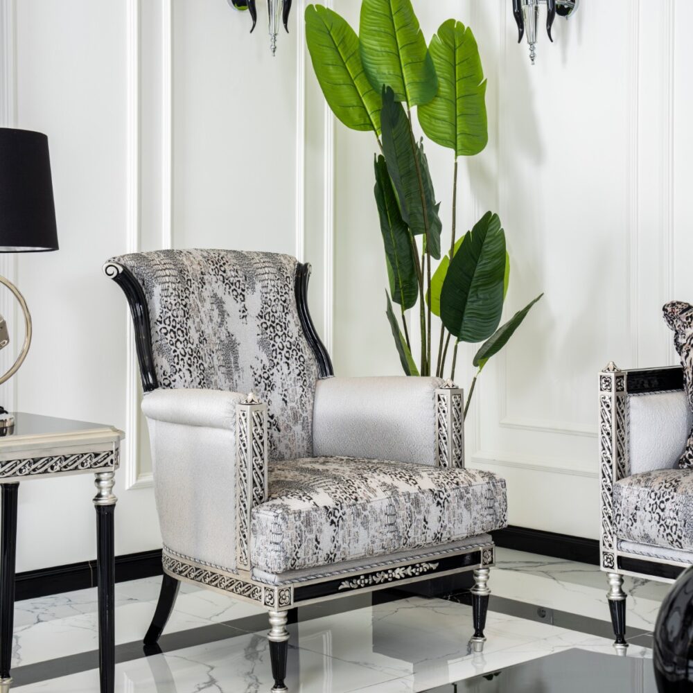 Luxurious living room with silver snakeskin chairs and a tall green plant against white paneled walls, accented by black lamps.