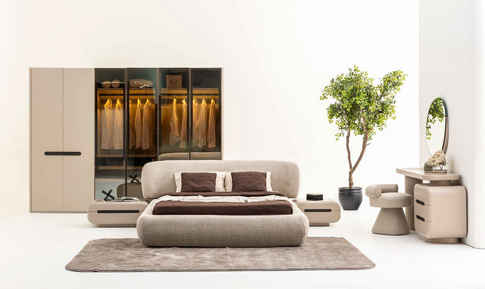 Modern minimalist bedroom showroom with a beige upholstered bed, matching wardrobes, and a light rug.