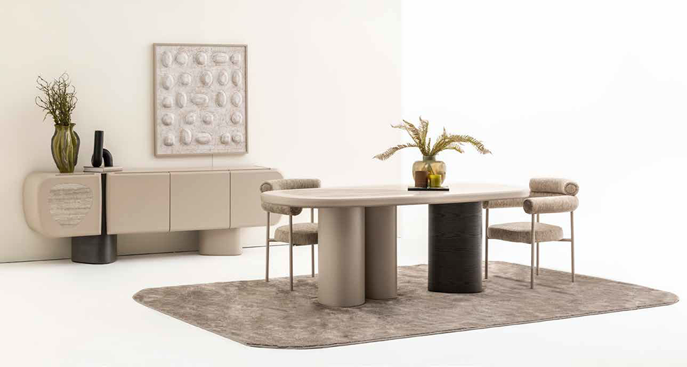 Modern dining room with an oval beige table, four upholstered chairs, and a textured rug; potted plant centerpiece on the table and sideboard with decor.