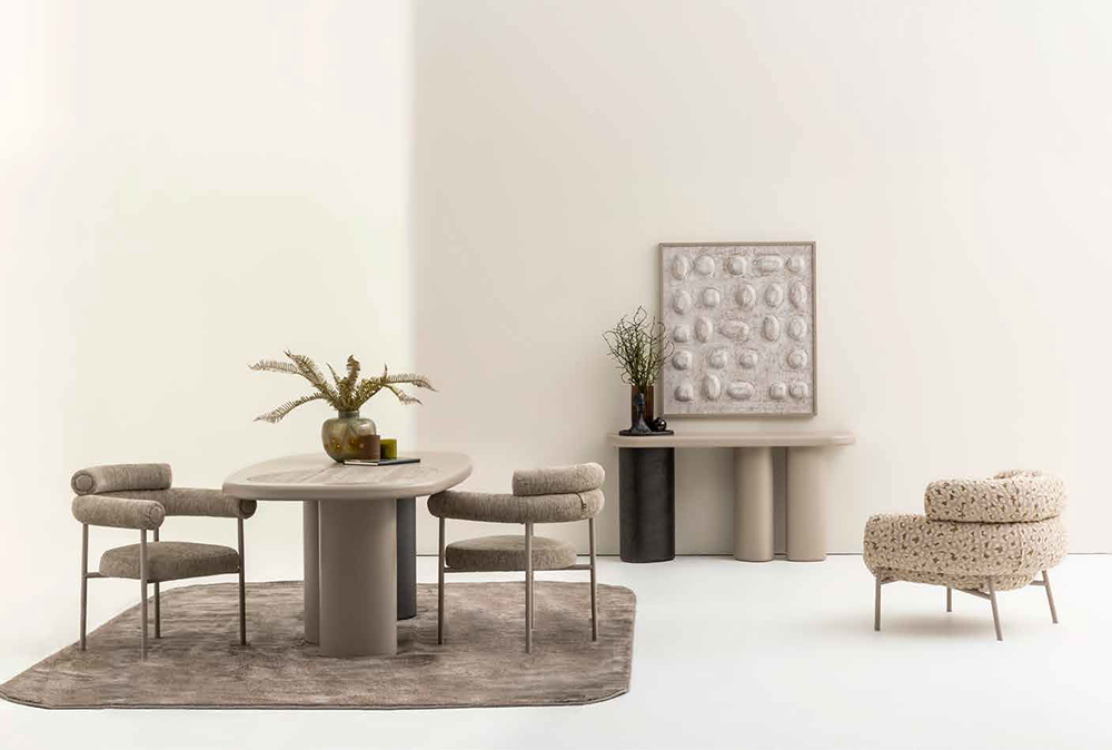 Minimal beige dining nook with a round table and four cushioned chairs on a soft rug against pale walls.