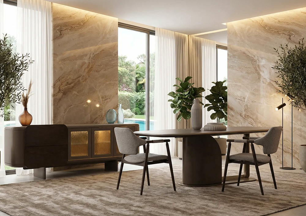 Modern dining area with a round table, four grey chairs, a dark sideboard, and marble walls bathed in natural light from large windows.
