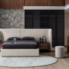 Luxurious modern bedroom with a beige upholstered platform bed dark bedding and wood nightstands against a stone accent wall