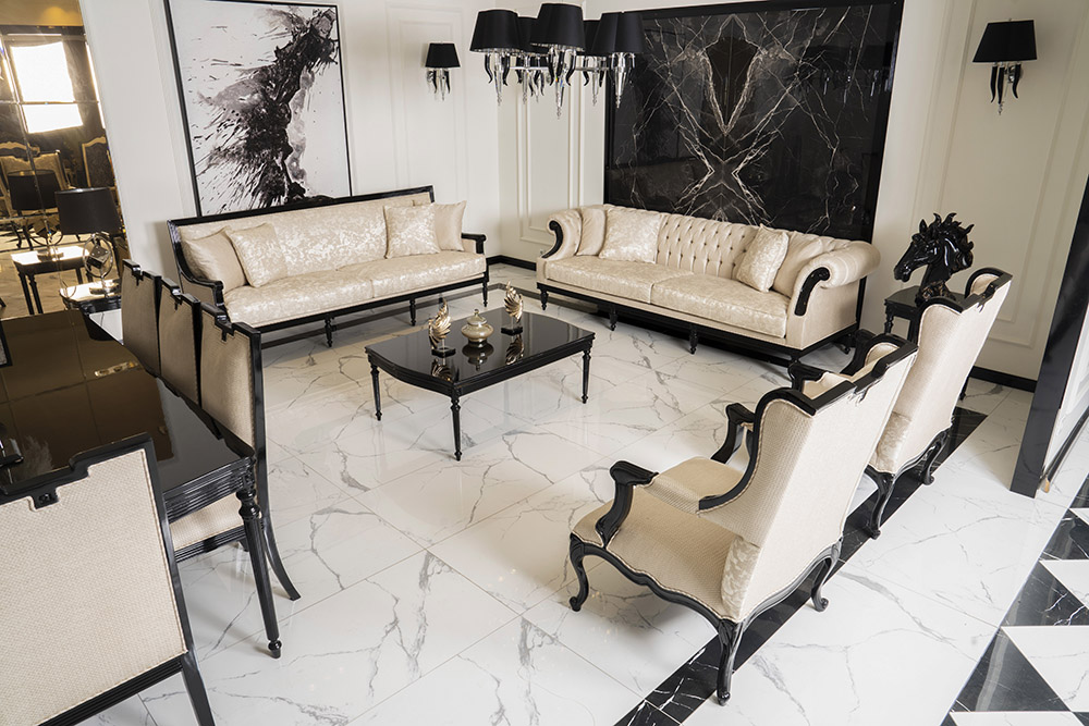 Luxurious cream-and-black living room with tufted sofas, matching chairs, and a glass coffee table on a white marble floor.