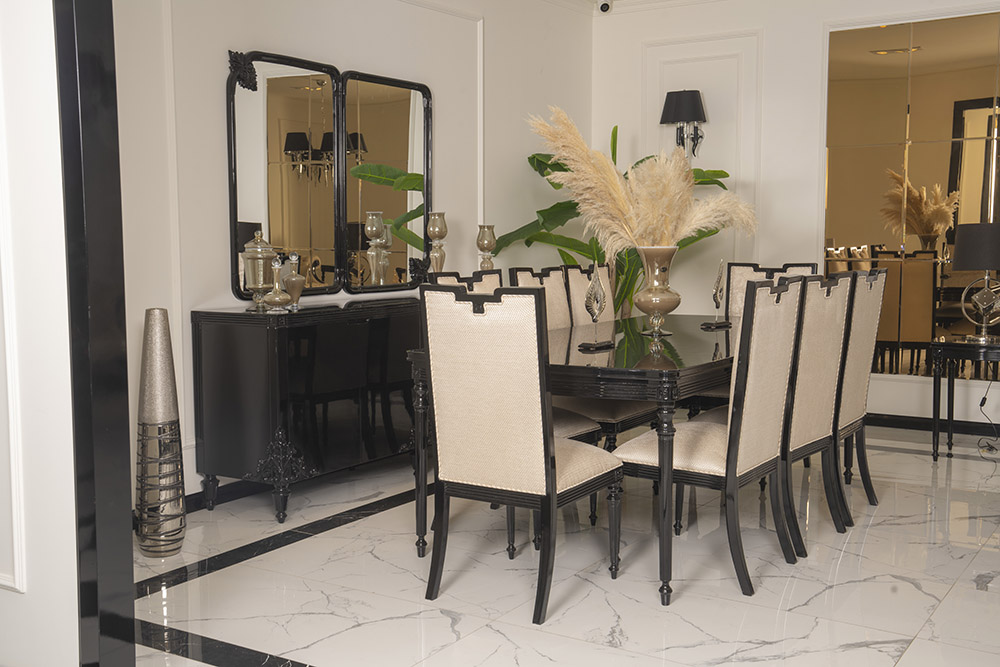 Elegant dining room with a black rectangular table, beige upholstered chairs, and a pampas grass centerpiece.