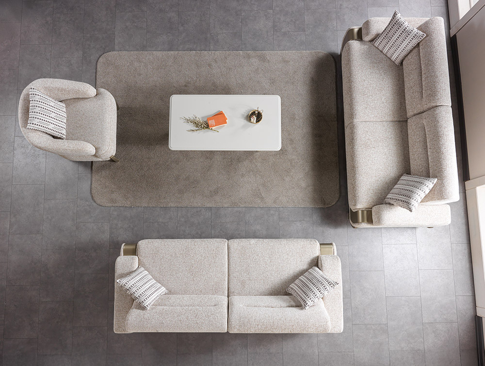 Top down view of a neutral living room with a beige sofa set around a white coffee table on a gray rug cushions on each seat