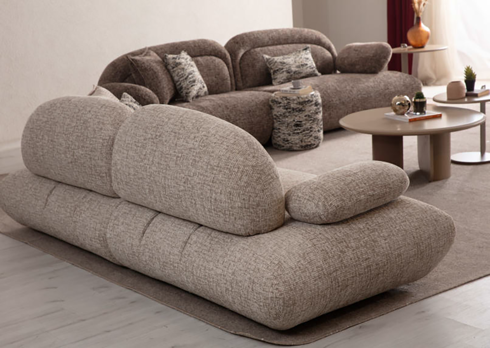 Beige modular sofa with rounded arms in a contemporary living room on a light rug, with matching cushions and round coffee tables nearby.