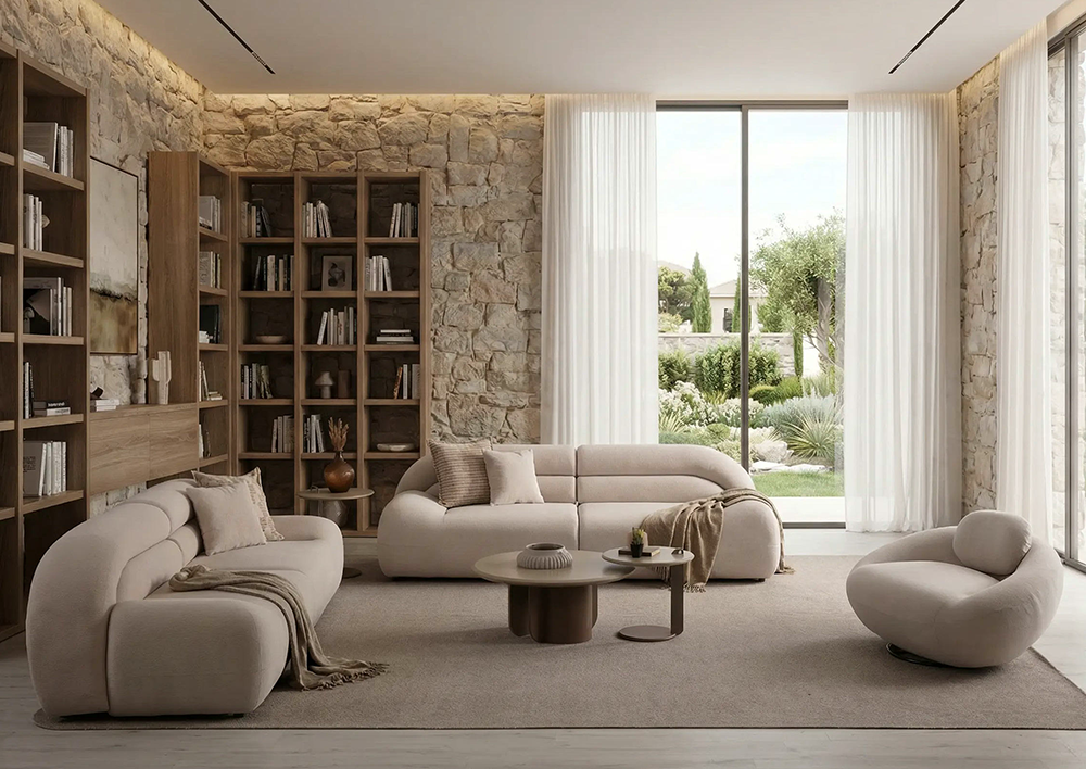 Living room with stone walls, large glass doors, and beige curved sofas around a round coffee table.