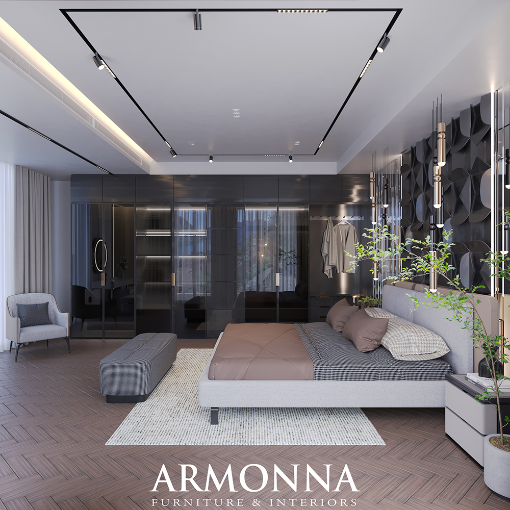 Luxurious modern bedroom showroom: platform bed with taupe bedding, plaid bench, gray chair, glass partition, dark built-in wardrobes, hanging lights, potted plants, and a textured rug; ARMONNA Furniture & Interiors logo at the bottom.