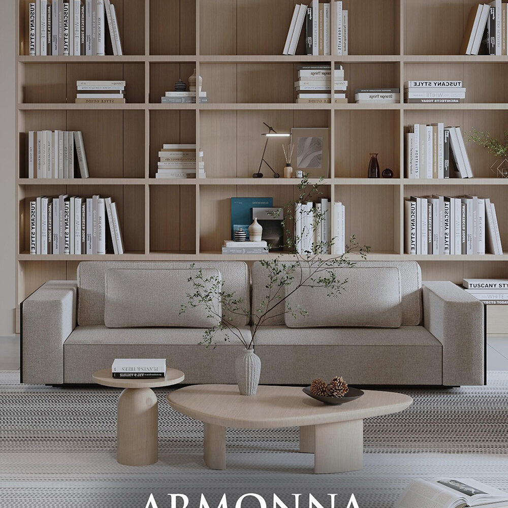 Neutral-toned living room featuring a large built-in wooden bookshelf wall, a beige sofa, and two round wooden coffee tables with a vase and pinecones; ARMONNA Furniture & Interiors branding.