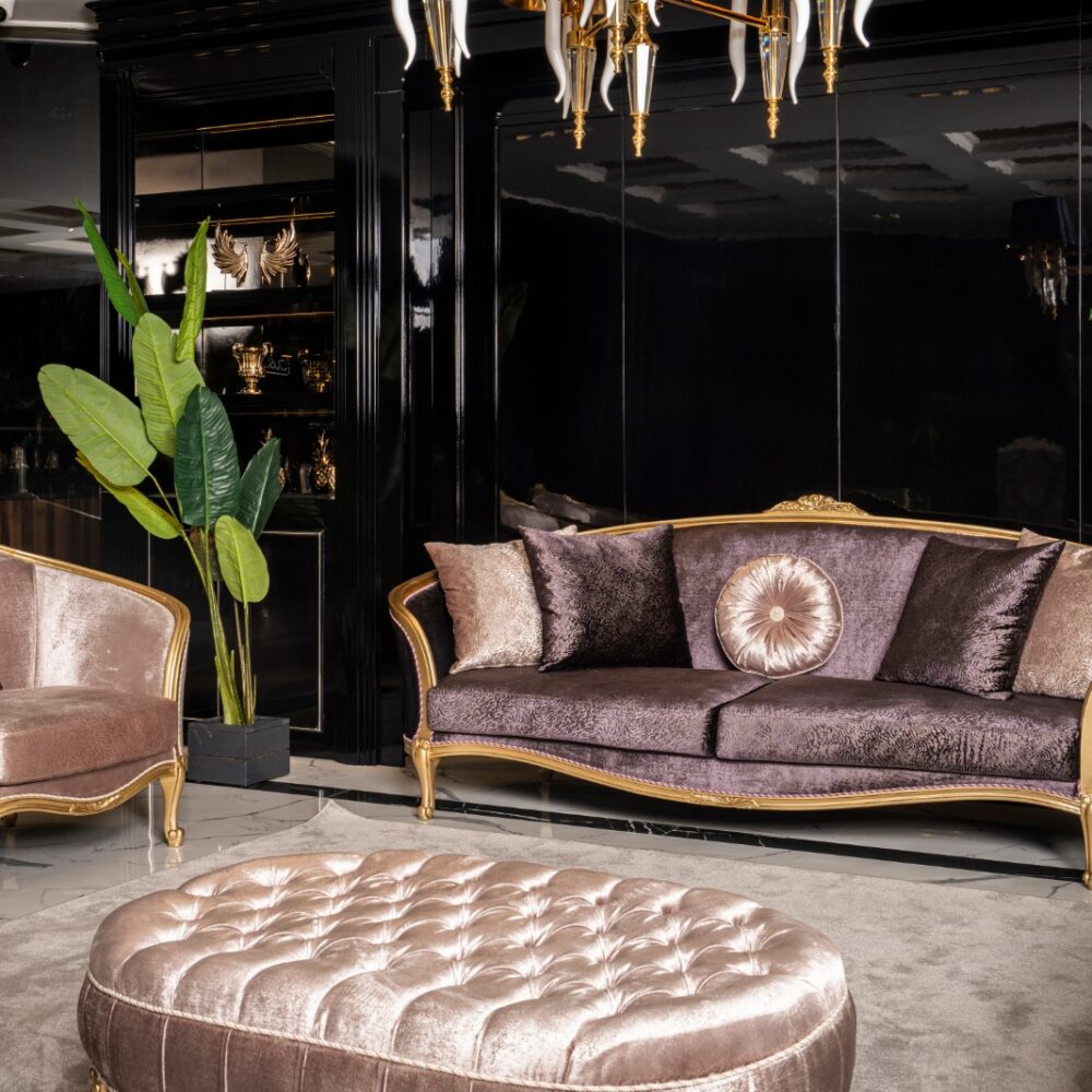 Luxurious living room with purple velvet sofa set, gold trim, and matching ottoman in front, black mirrored wall behind.