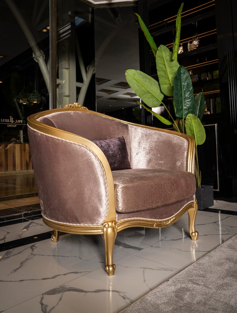 Verona Classic Set 20 Armonna Luxurious pink velvet armchair with a gold frame and carved details in a marble floored lobby with a large green plant nearby