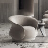Gray circular lounge chair in a modern living room with a small side table and a sofa in the background