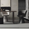 Modern conference style setup with a wooden table and two sculptural pedestal chairs in neutral tones against a textured wall backdrop