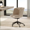 Cream upholstered swivel office chair on five caster wheels at a glass desk in a bright modern home office with a coastal view