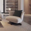 White lounge chair with a dark green pillow sits on a patterned beige rug in a modern living room with a wooden door and shelving in the background