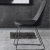 Black upholstered chair with metal sled legs in a modern room with a dark textured wall behind it
