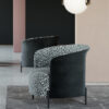 Curved lounge chair with dark blue exterior and patterned gray fabric interior in a modern room with pendant lights