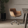 Orange swivel office chair on a metal wheeled base beside a wooden desk in a modern workspace
