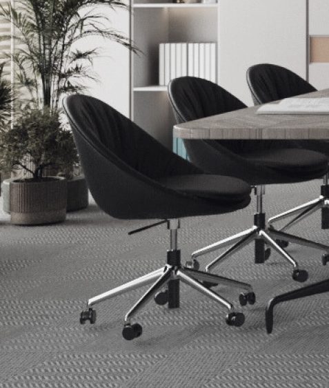 dreamoficce Armonna Three black swivel chairs surround a wooden conference table in a bright meeting room with a potted plant and shelves in the background