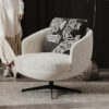 Round beige fabric swivel chair with black metal base and a blackandwhite patterned cushion in a cozy living room
