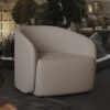 Beige curved armchair in a modern showroom with greenery and glass walls behind it