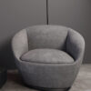 Gray rounded armchair with a cushioned seat in a modern minimal setting