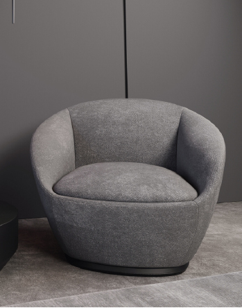 Gray rounded armchair with a cushioned seat in a modern, minimal setting.
