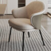 Beige upholstered armchair with a curved back and black legs on a striped rug in a modern living room