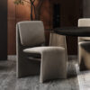 Modern gray upholstered chair beside a round dark wood table in a stylish dimly lit interior