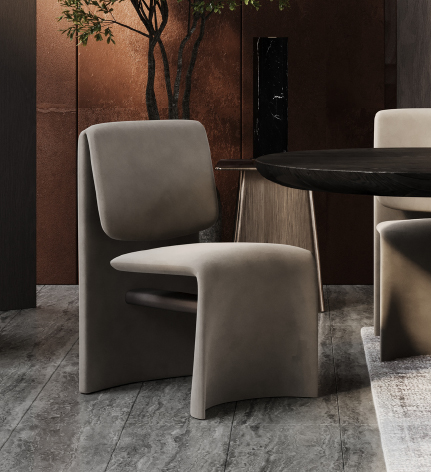 Modern gray upholstered chair beside a round dark wood table in a stylish, dimly lit interior.