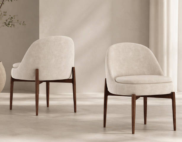 Two beige upholstered lounge chairs with dark wooden legs in a minimalist room.