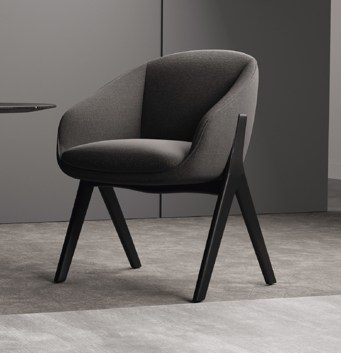 Gray upholstered lounge chair with black angled legs in a minimal office corner of a neutral room.