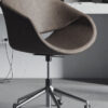 stiloffice Armonna Brown curved swivel office chair with a metal wheeled base in a modern workspace laptop and desk visible in the background