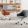 summeroffice Armonna Two swivel office chairs on wheels in a minimalist room with a magazine filled wall shelf behind them