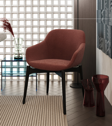 Red upholstered lounge chair with black legs in a modern living space, beside a glass side table and decorative vases.