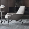 Grey upholstered lounge chair with black metal legs in a modern living room setting