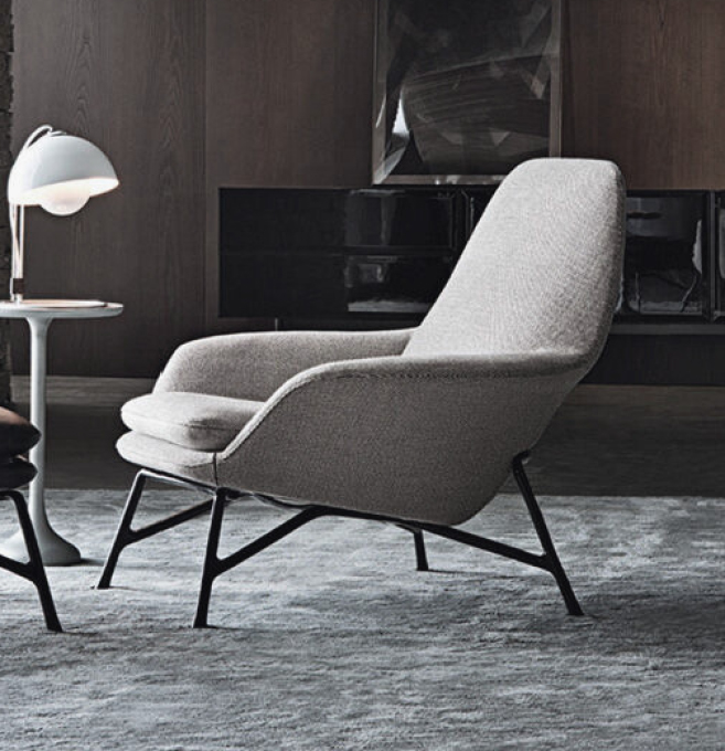 Grey upholstered lounge chair with black metal legs in a modern living room setting